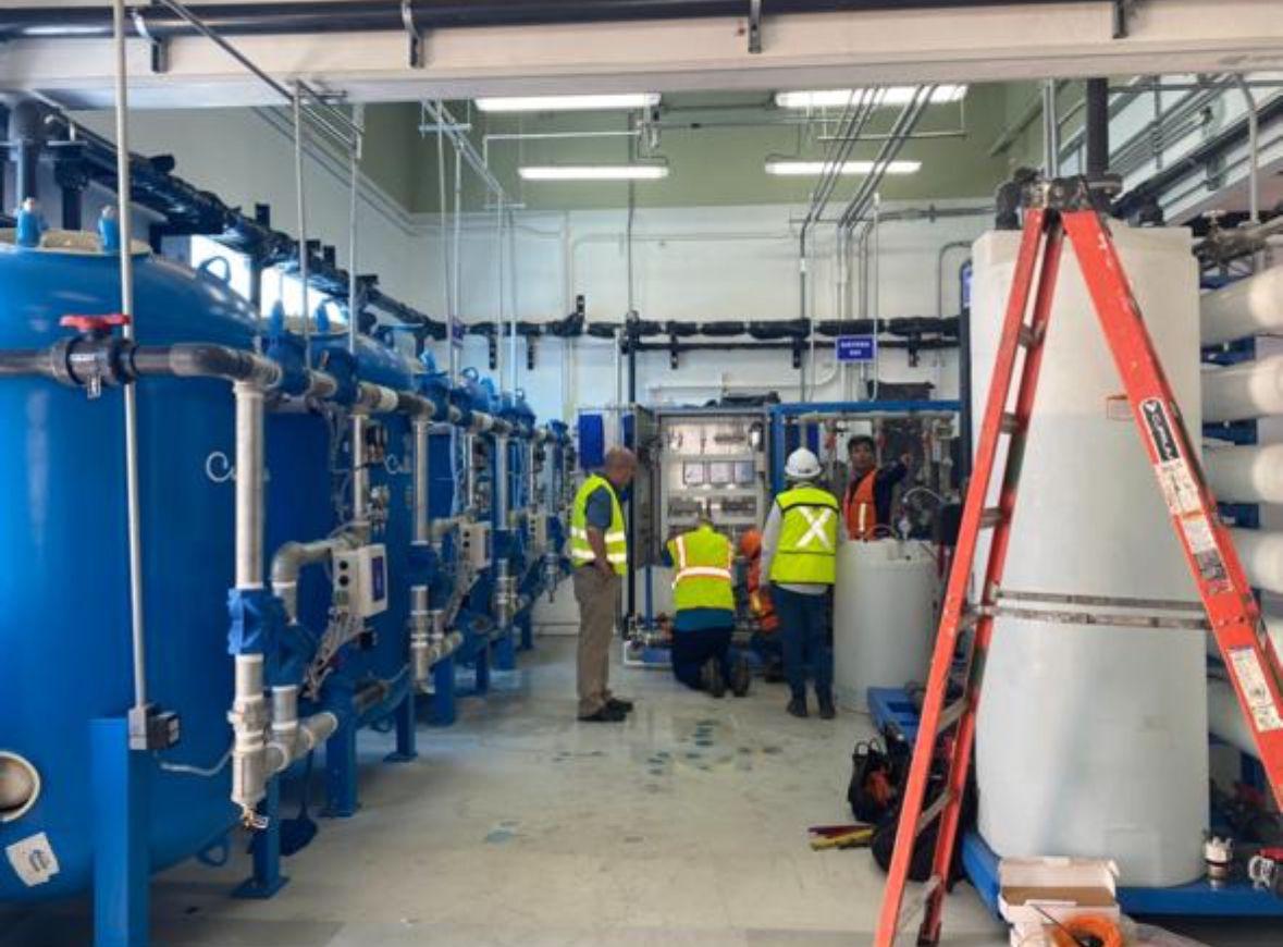 Técnicos trabajando en planta de filtración con recipientes a presión y módulos de ósmosis inversa